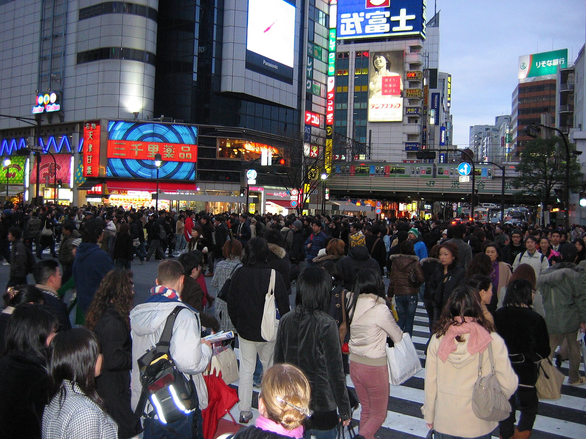 Crowds crossing the Shibuya scramble crossing in Tokyo at dusk