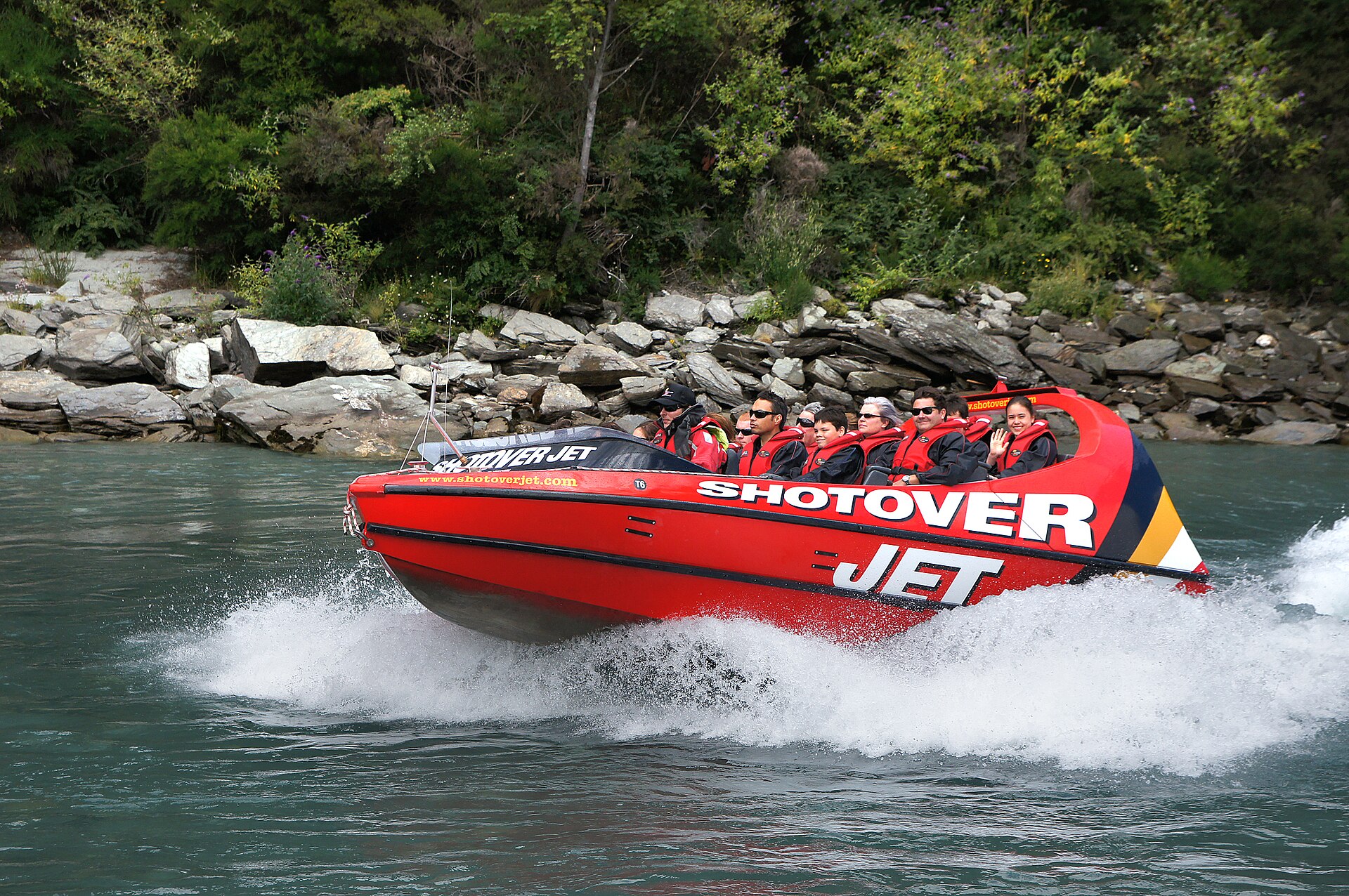 Jet boat speeding through a narrow canyon on the Shotover River near Queenstown