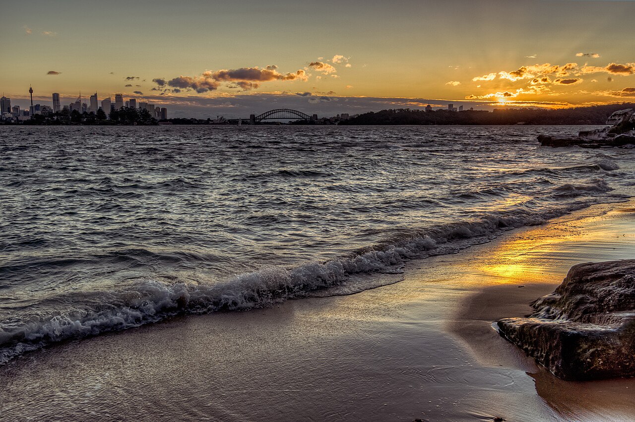 Sunset over Milk Beach in Vaucluse with the Sydney skyline and Harbour Bridge across the water