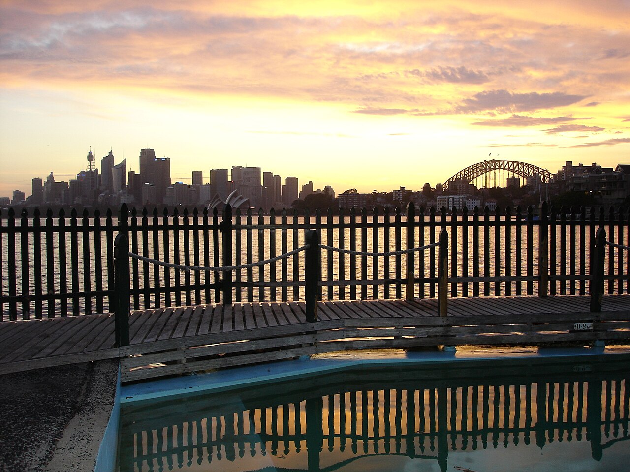 Sunset over Sydney Harbour from MacCallum Pool at Cremorne Point, with the city skyline, Opera House and Harbour Bridge