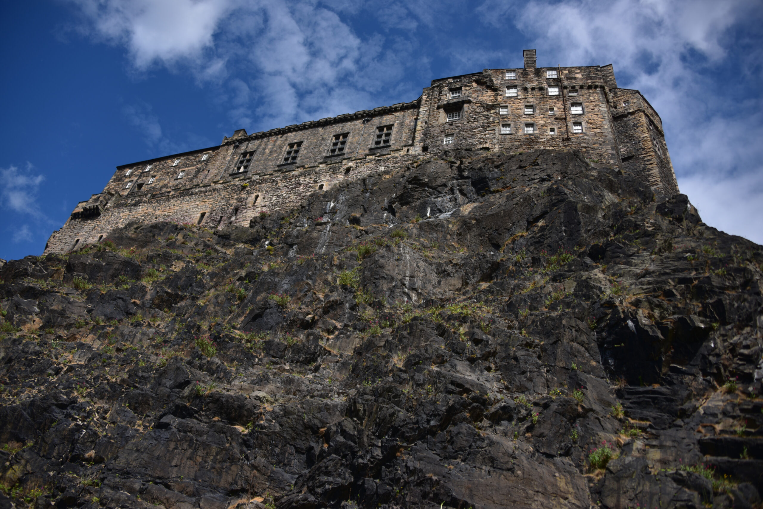 Edinburgh Castle towering over volcanic Castle Rock against a bright blue sky