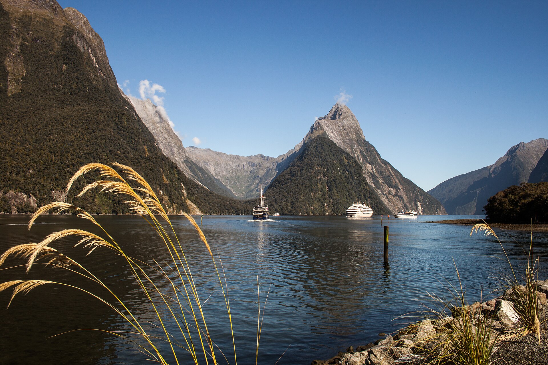 Tour boats cruising on Milford Sound in front of the towering Mitre Peak