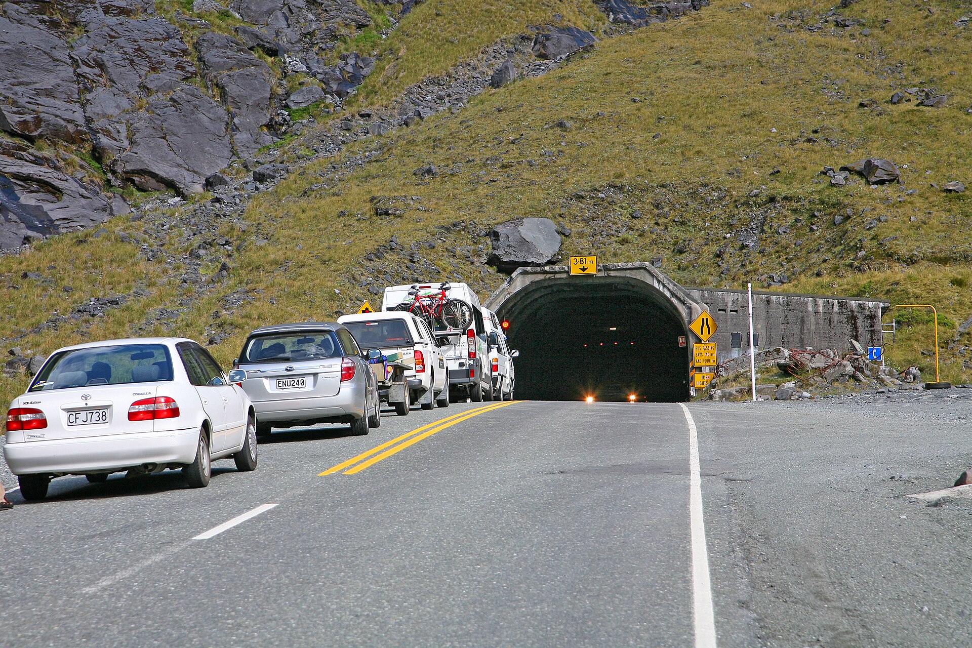 Cars emerging from the dark portal of the Homer Tunnel on the road to Milford Sound