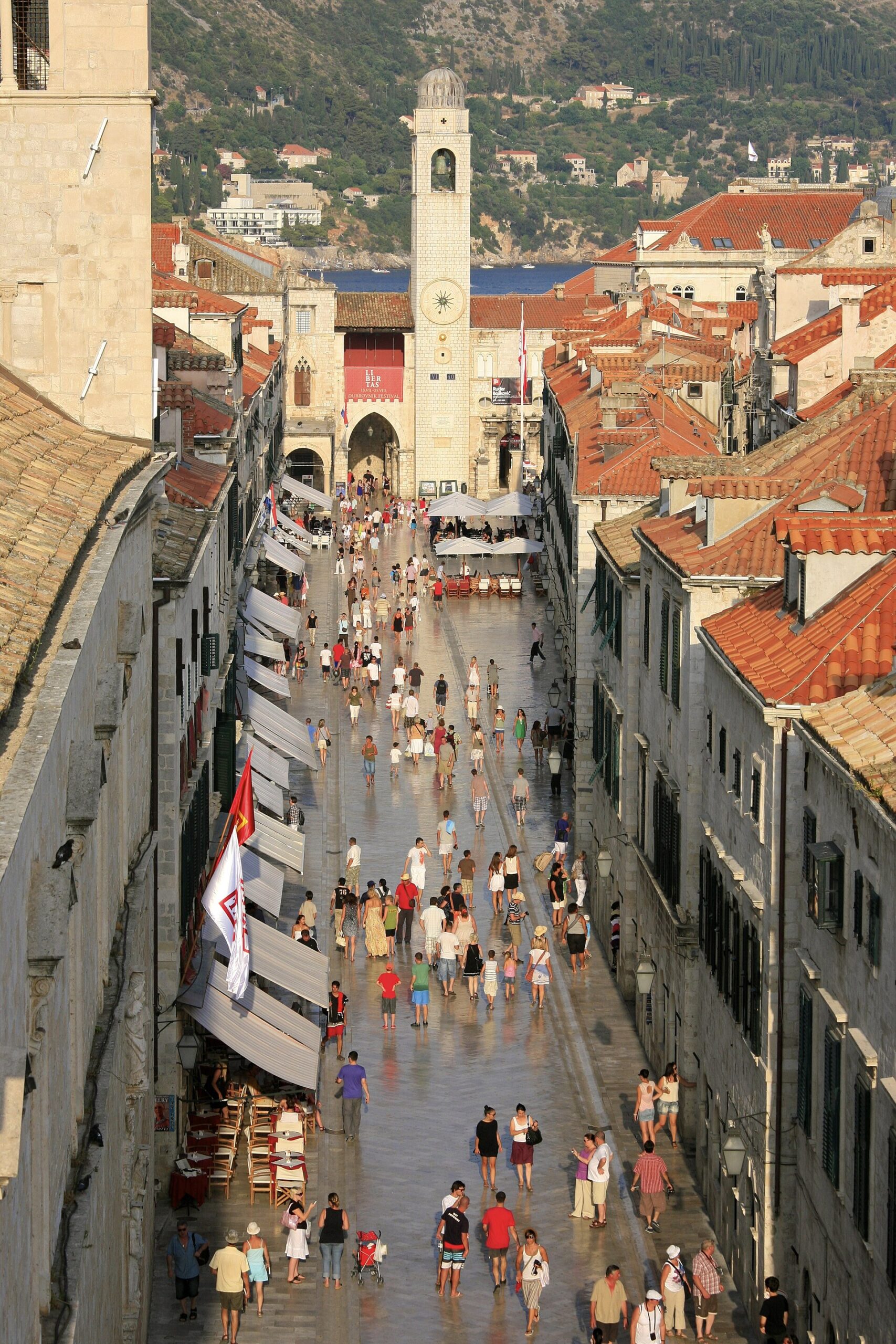 Crowds walking along the Stradun, Dubrovnik's limestone main street, with the clock tower ahead