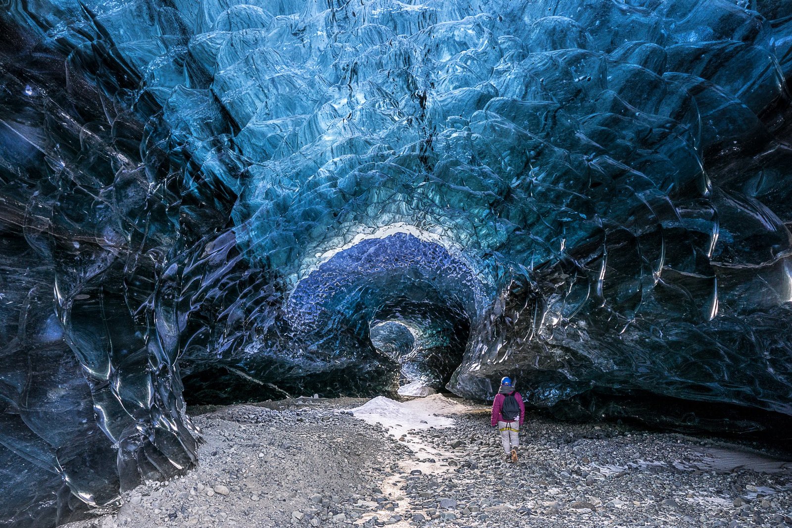 A visitor standing inside a natural blue ice cave in Breiðamerkurjökull
