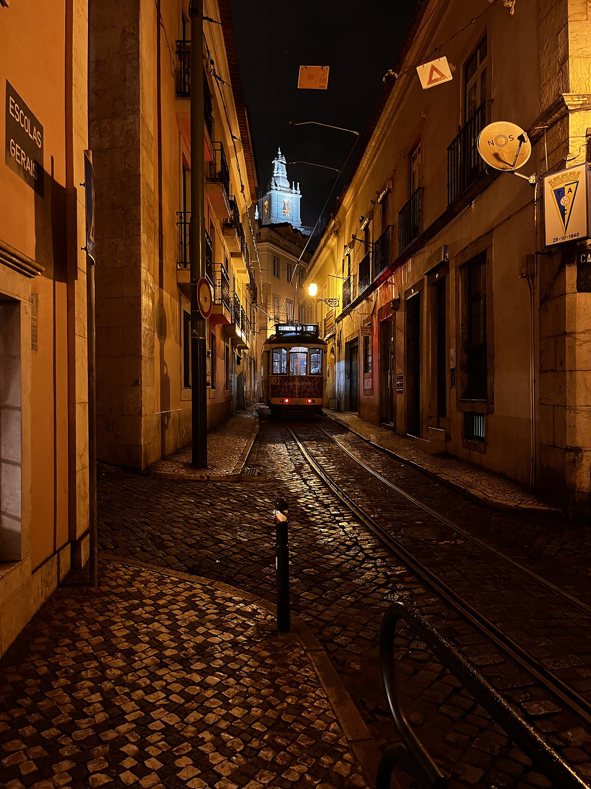A yellow Tram 28 climbing a steep Lisbon street