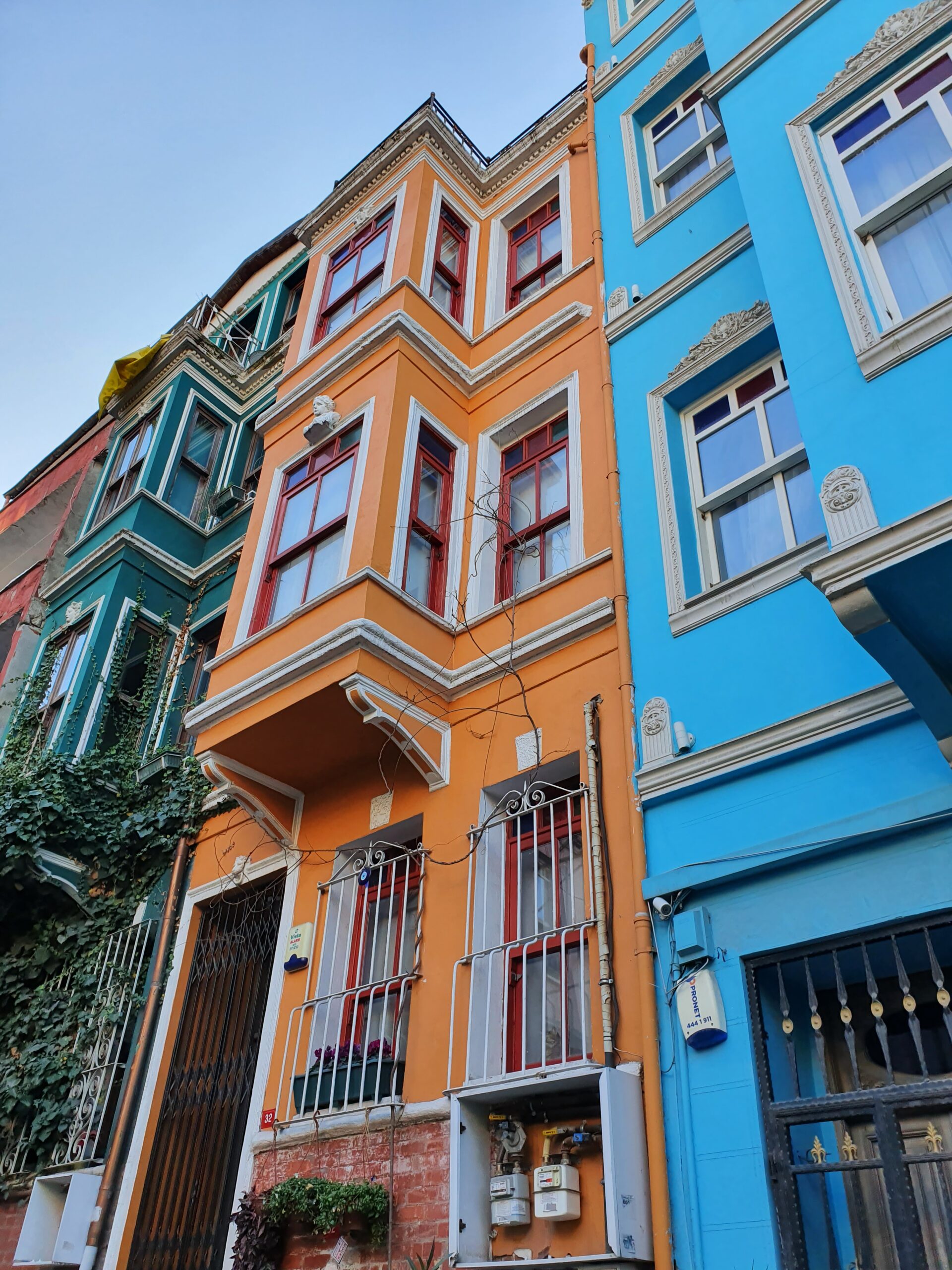 Brightly painted row houses in pastel pinks, yellows, and blues line a cobbled street in Balat, Istanbul.