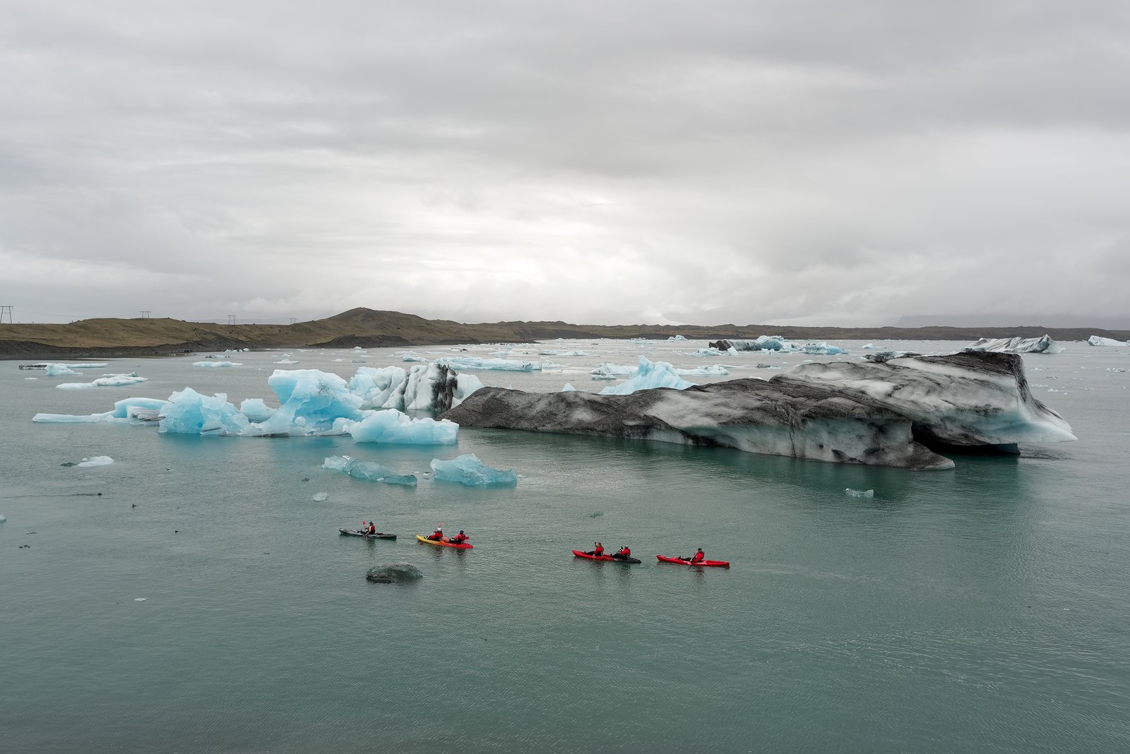 Kayakers paddling among blue icebergs at Jökulsárlón glacier lagoon