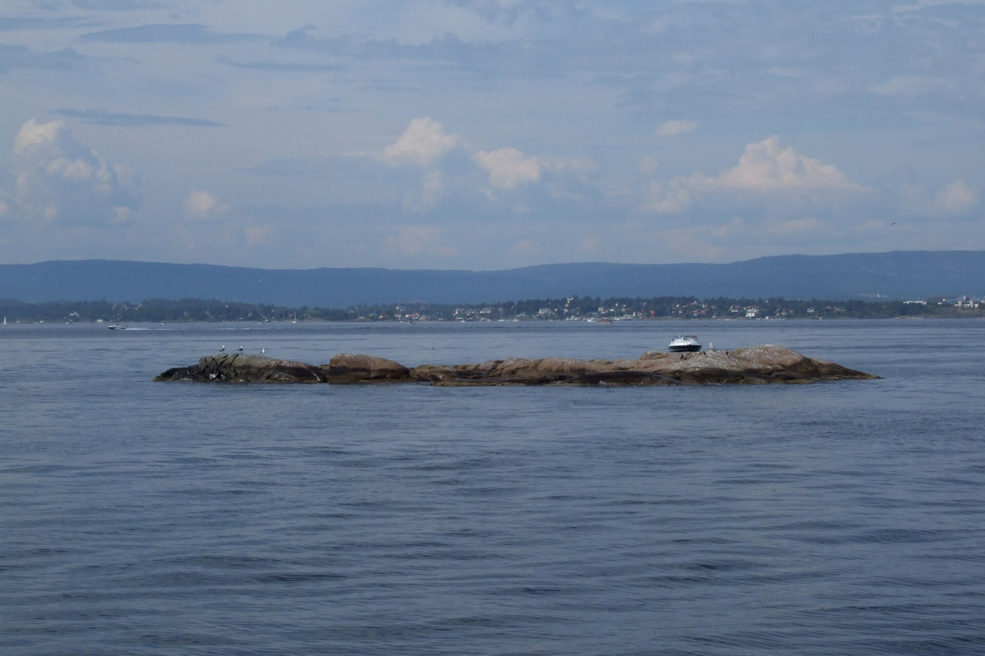 A small green island in the calm waters of the Oslofjord near Oslo