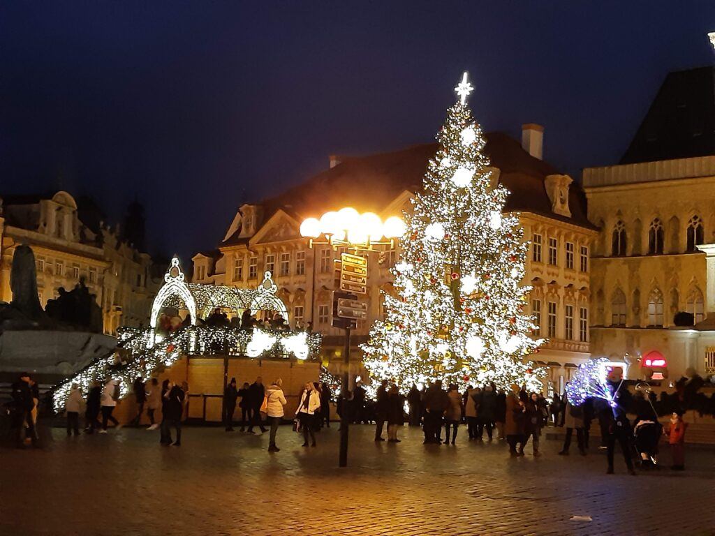 Lit Christmas tree and market stalls in Prague's Old Town Square at night